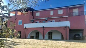 A two-story building with a red facade, arched doorways, and a covered patio area. - Bed & Breakfast Cilento (San Mauro Cilento)