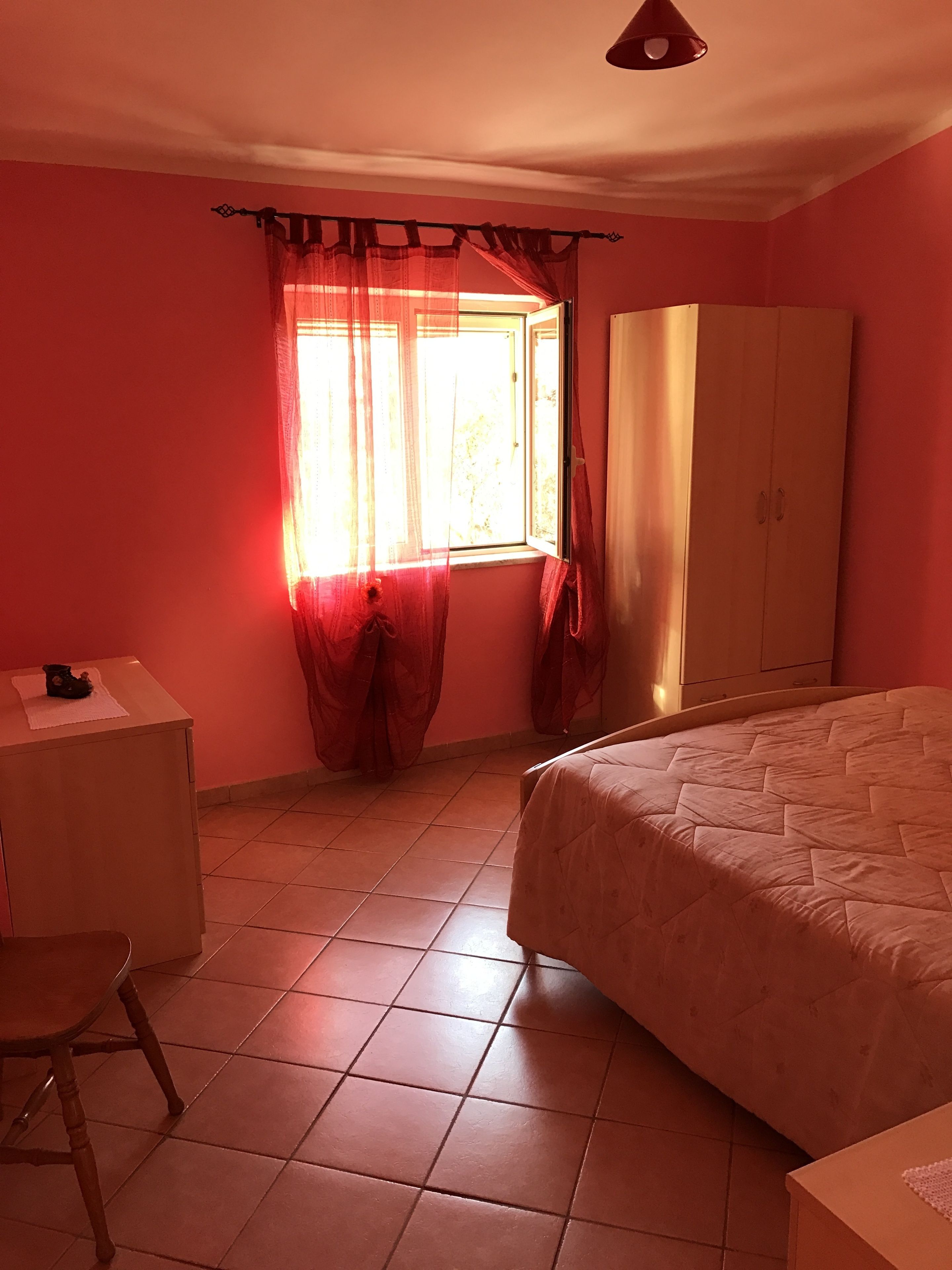 A bedroom with a bed, a wardrobe, a desk, and a chair.