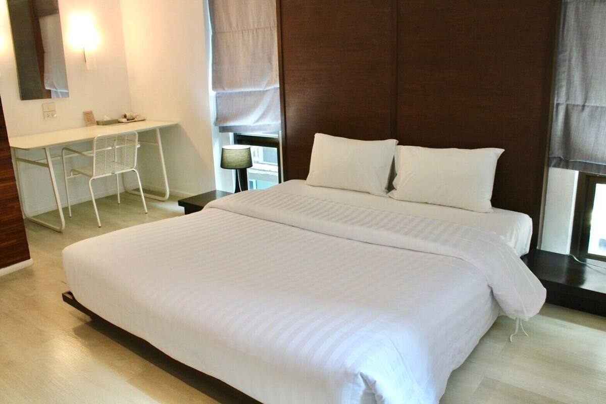 A hotel room with a large bed, a desk, and a chair.