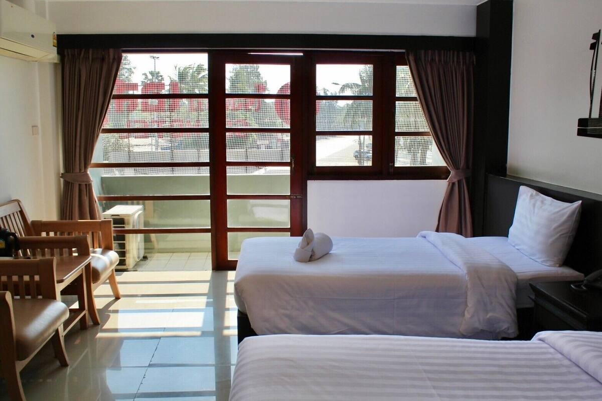 A hotel room with two beds, a desk, and a chair.