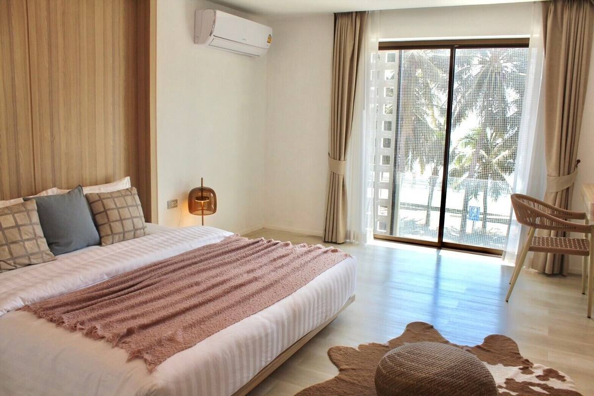 A bedroom with a bed, a chair, a window, and a door.