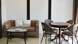 Une pièce comprenant un canapé marron à motifs, une table basse en verre et une table à manger en bois avec quatre chaises.