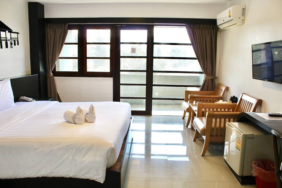 A hotel room with a bed, a desk, a chair, and a television.