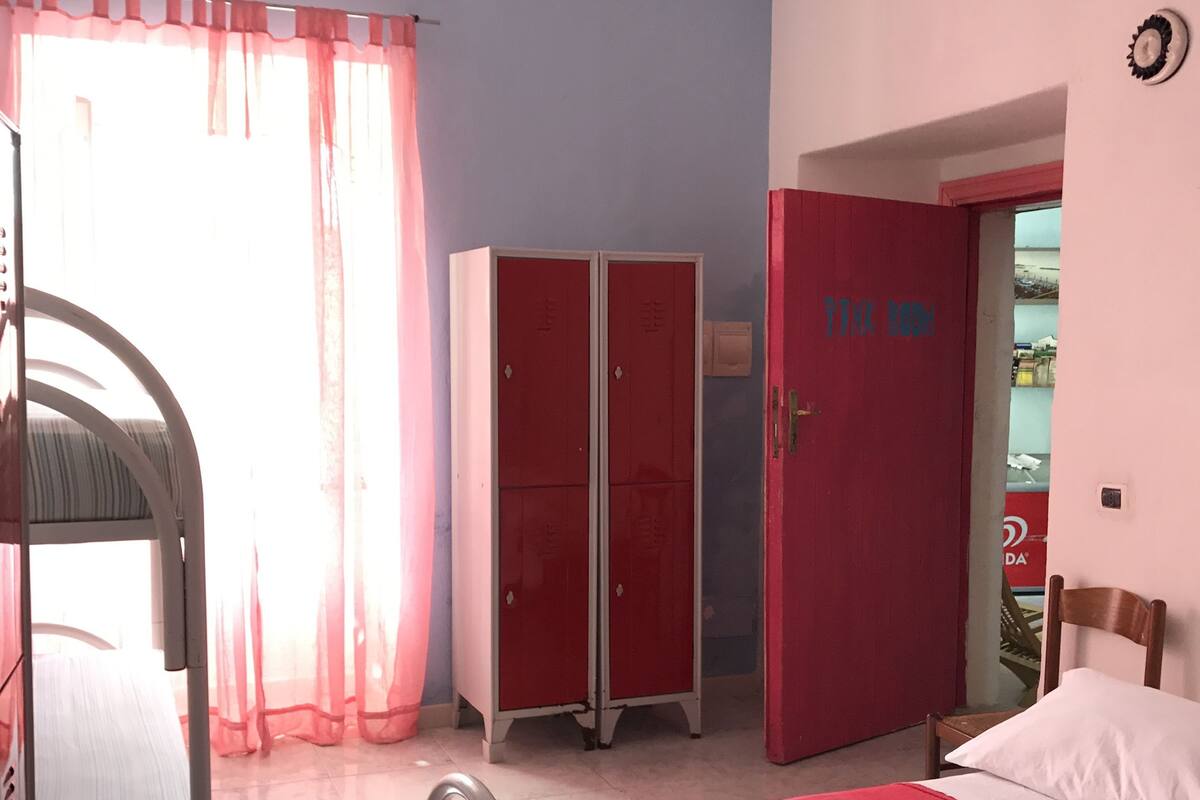 Ein Schlafzimmer mit einem Bett, einem Schreibtisch, einem Stuhl, einem Kleiderschrank und einer Tür mit der Aufschrift 'JUNK ROOM'.