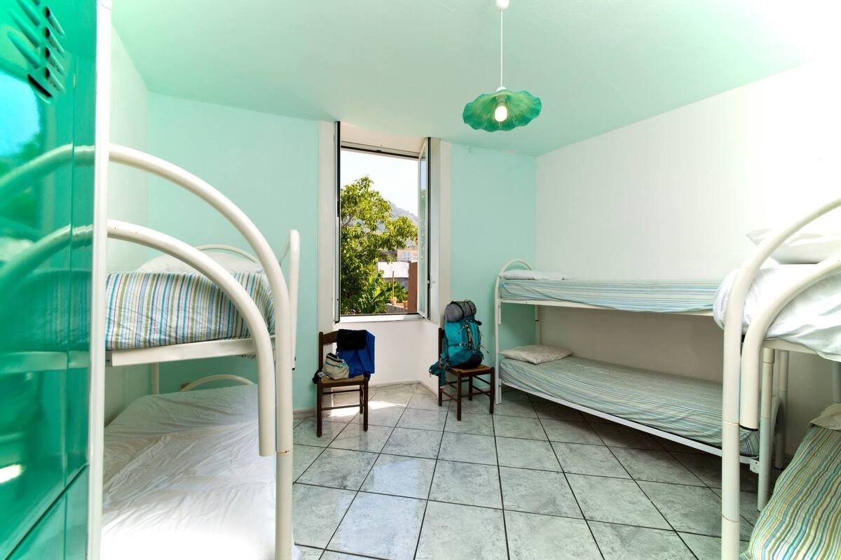 Ein Zimmer mit Etagenbetten, einem Fenster und einem Sessel.