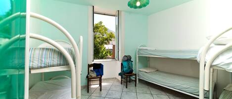 A room with bunk beds, a window, and a chair.