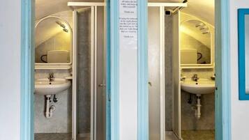 A bathroom with two sinks, a shower, and a mirror. There is a sign with instructions for using the bathroom.