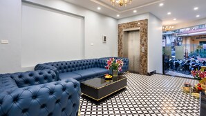 A modern living room with a blue sofa, a black coffee table, and a patterned floor. - Memory Legends Hotel (Hanoi)