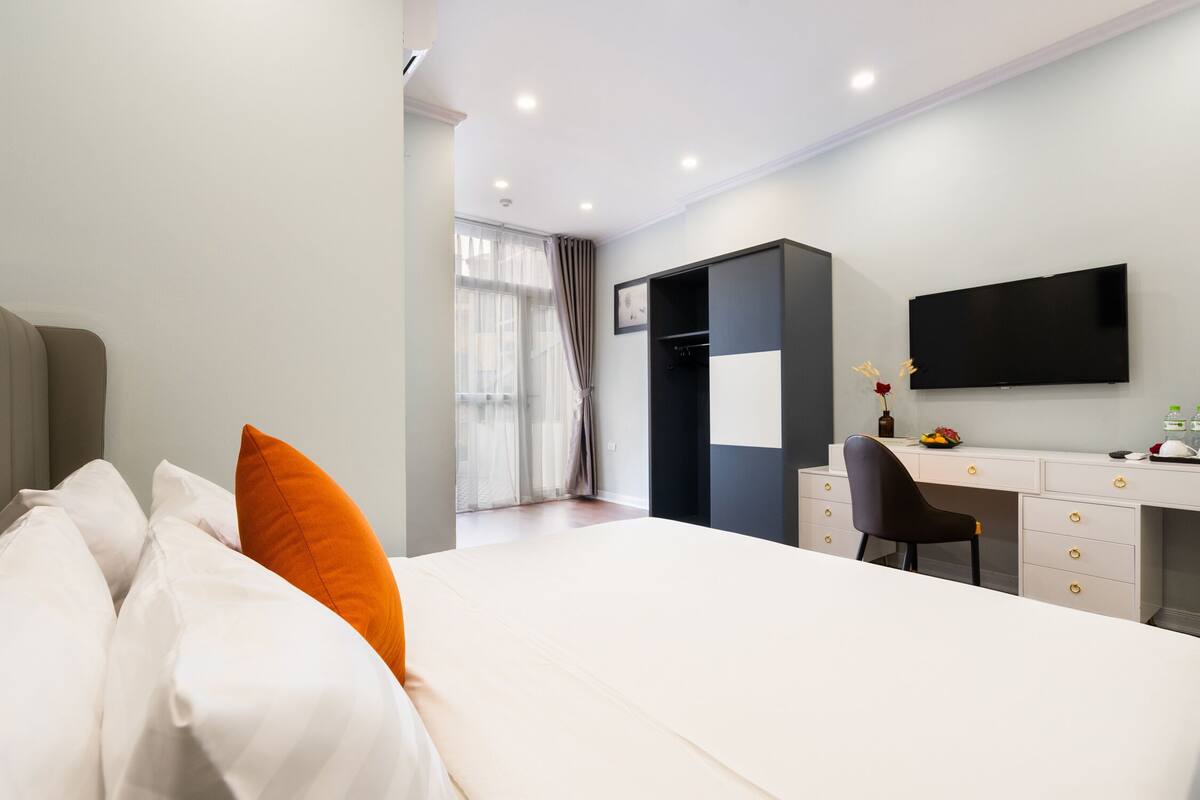 A modern hotel room with a large bed, a desk, and a television.