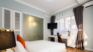 A hotel room with a bed, a desk with a computer, a TV, and a window with curtains. - Memory Legends Hotel (Hanoi)