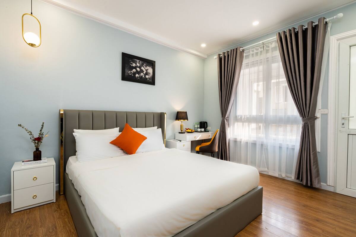 A neatly arranged hotel room with a large bed, a desk, and a chair.