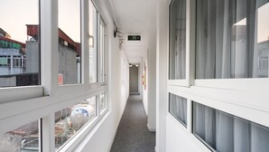 A corridor with large windows on one side, a grey carpet, and a sign indicating an exit. - Memory Legends Hotel (Hanoi)