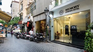 A street with parked motorcycles and a hotel named 'Memory Legends Hotel' with a grand opening sign. - Memory Legends Hotel (Hanoi)