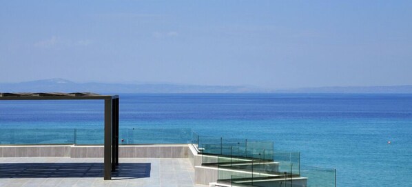 A modern outdoor terrace with a clear view of the sea and distant mountains. - Ostria Sea Side Hotel (Kassandra)