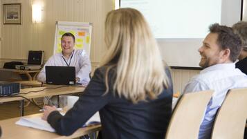 A conference room with a whiteboard, a laptop, and a projector.