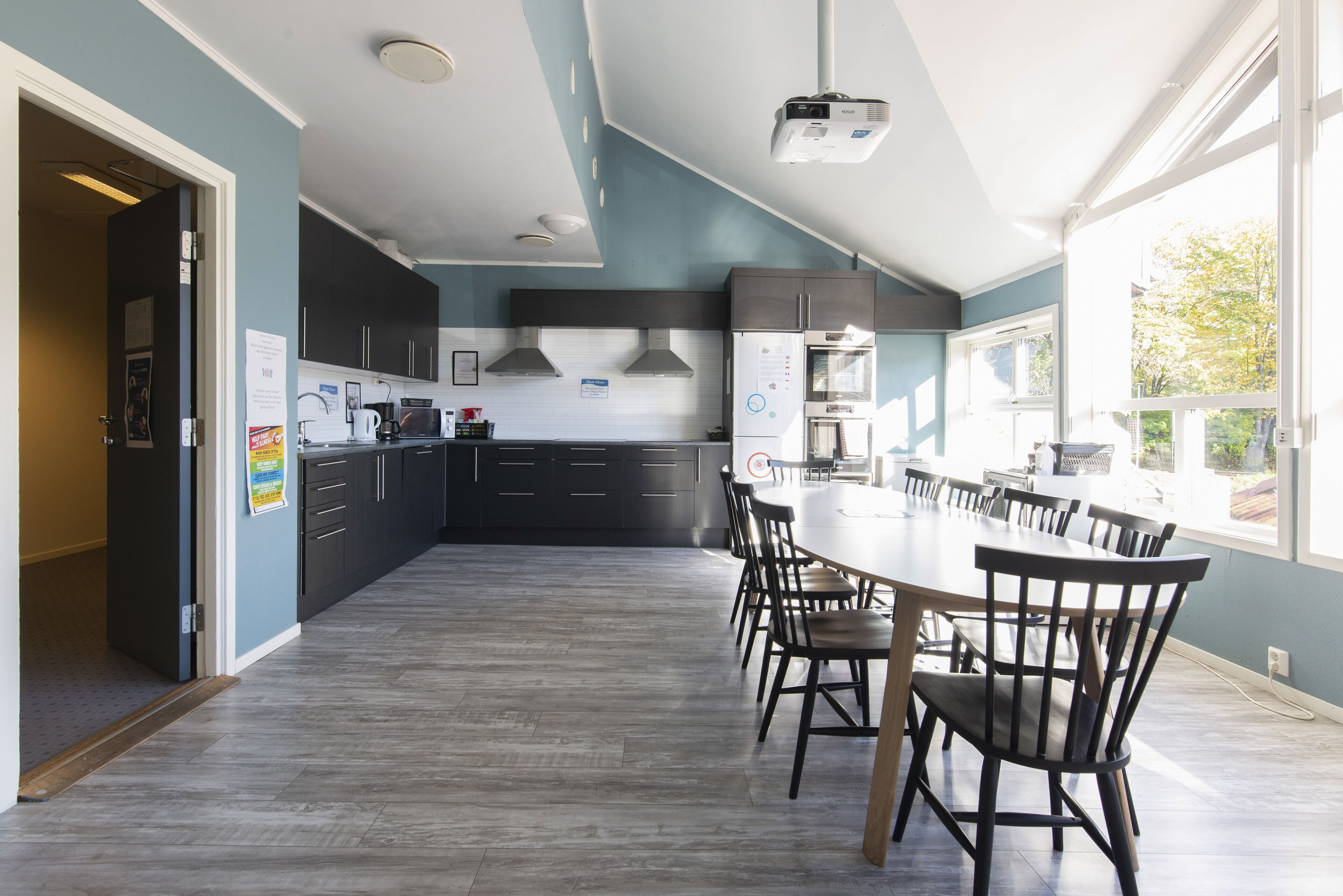 A modern kitchen with dark cabinets, a large island, and a dining area with chairs.