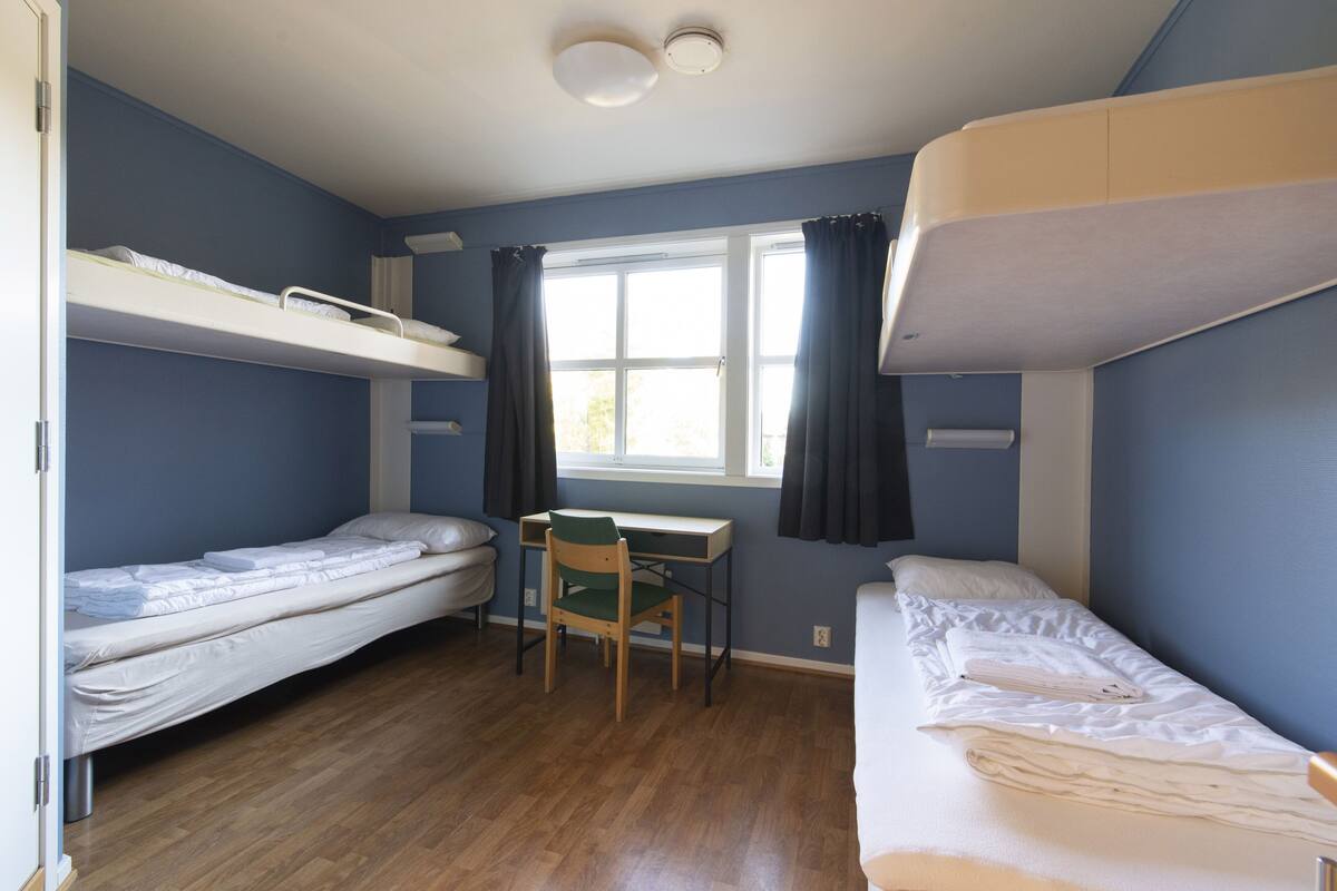 Ein Schlafsaalzimmer mit Etagenbetten, einem Schreibtisch und einem Stuhl.