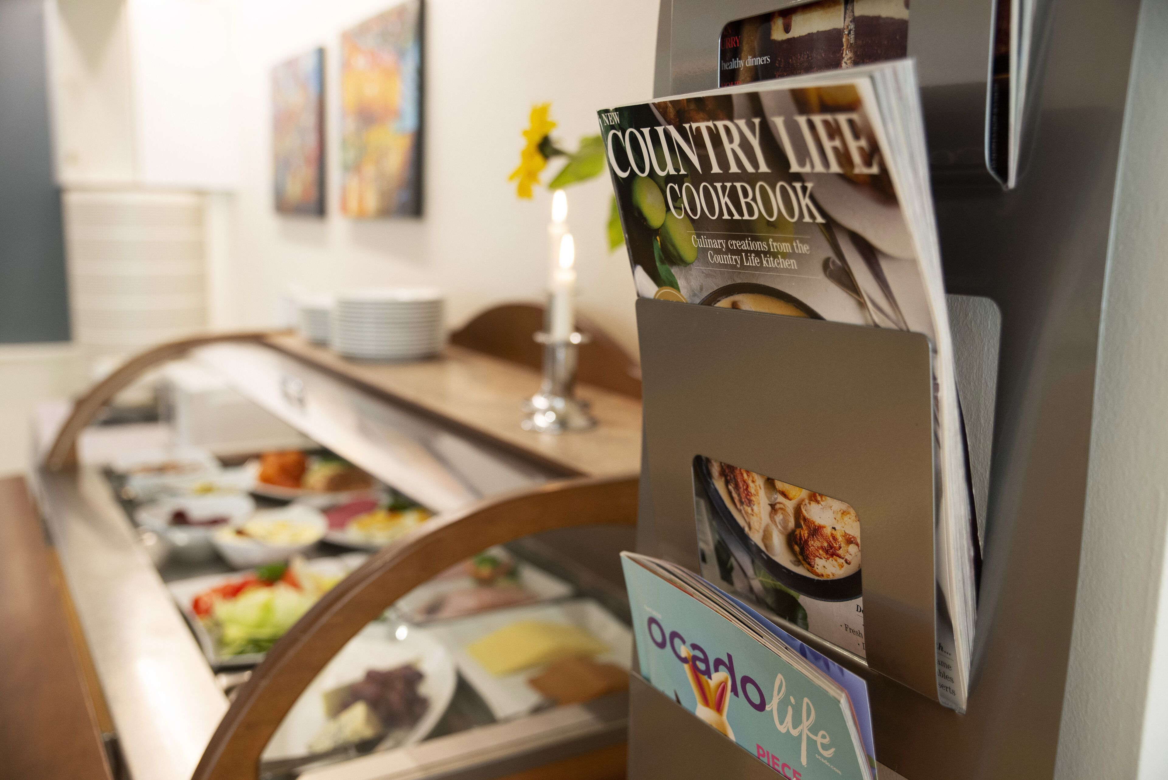 Montaje de bufé con diversos alimentos y un atril con un libro de cocina 'Country Life Cookbook'.