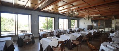 Un restaurant amb diverses taules i caires, finestres grans i un sostre de fusta.