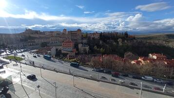 A cityscape with a prominent castle-like structure on a hill, a busy road with vehicles, and a clear sky.