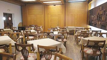 A dining area with multiple tables and chairs, wooden panel walls, and a ceiling with skylights.