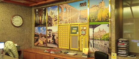 A reception desk with a clock, a telephone, and a bulletin board.
