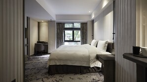 A modern hotel room with a large bed, a desk, and a view of the outdoors. - At Home Hotel Ximen (Taipei)