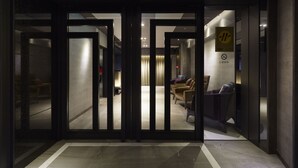 A hotel lobby with a modern design, featuring a reception desk, seating area, and a visible staircase. - At Home Hotel Ximen (Taipei)