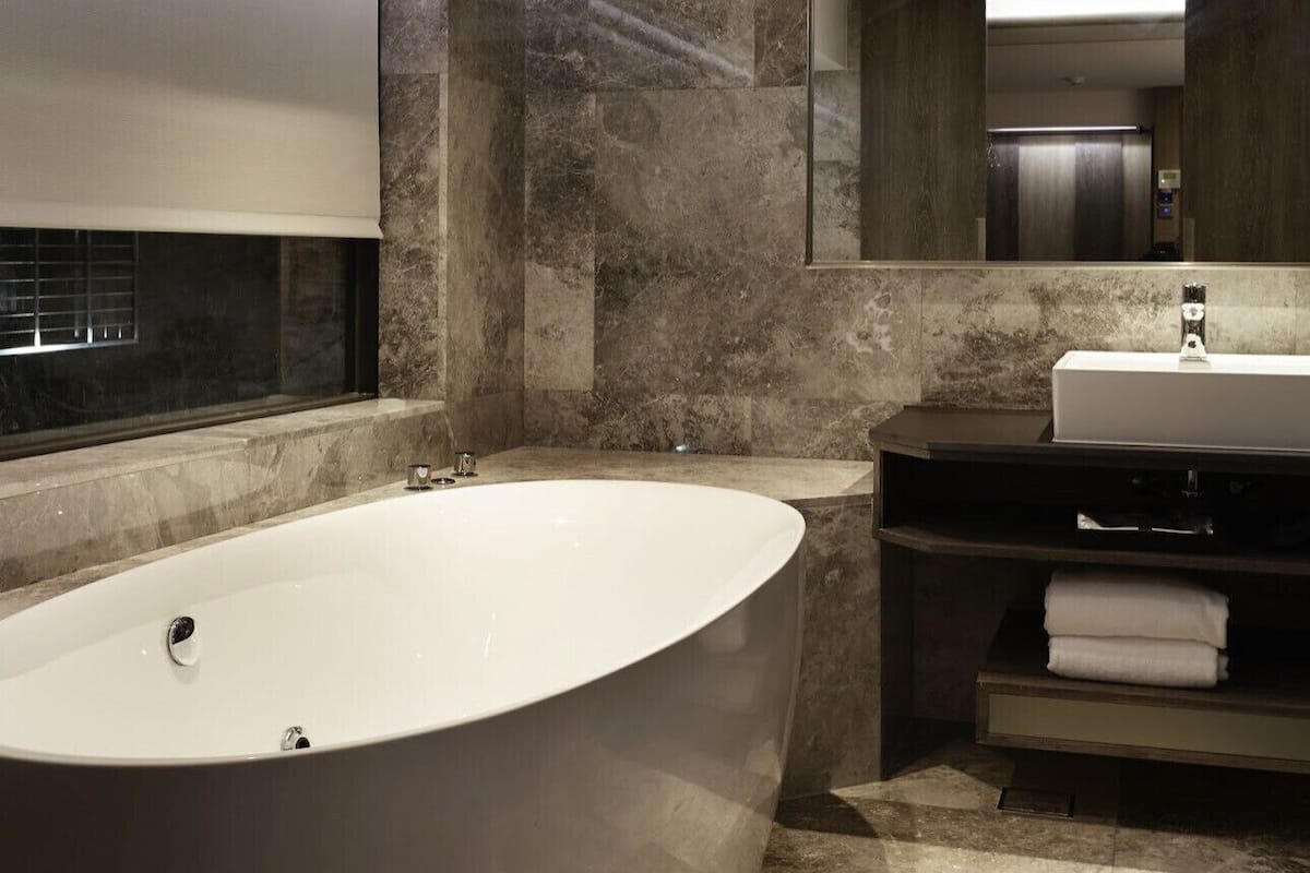 A modern bathroom with a freestanding bathtub, a large mirror, and a vanity with a sink.