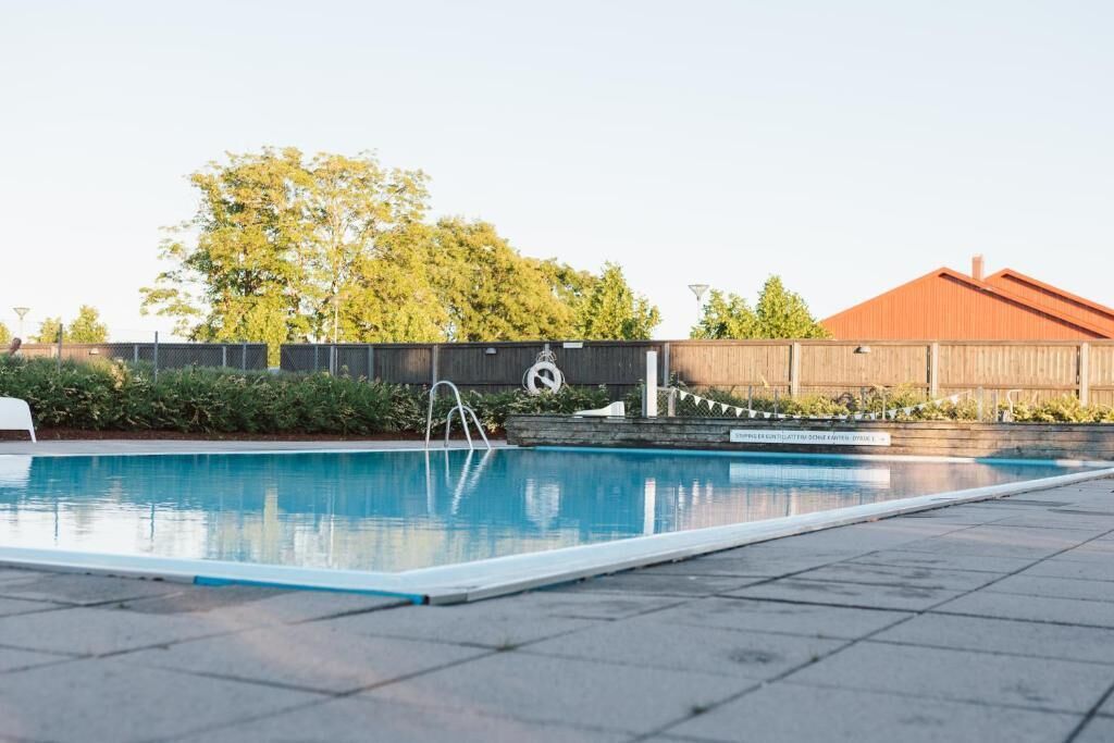 Una piscina con cerramiento de madera y un edificio al fondo.