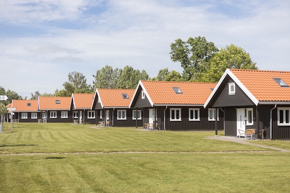 A row of identical cottages with orange tiled roofs, each featuring a small balcony and a door with a window. - Dal Gjestegaard (Horten)