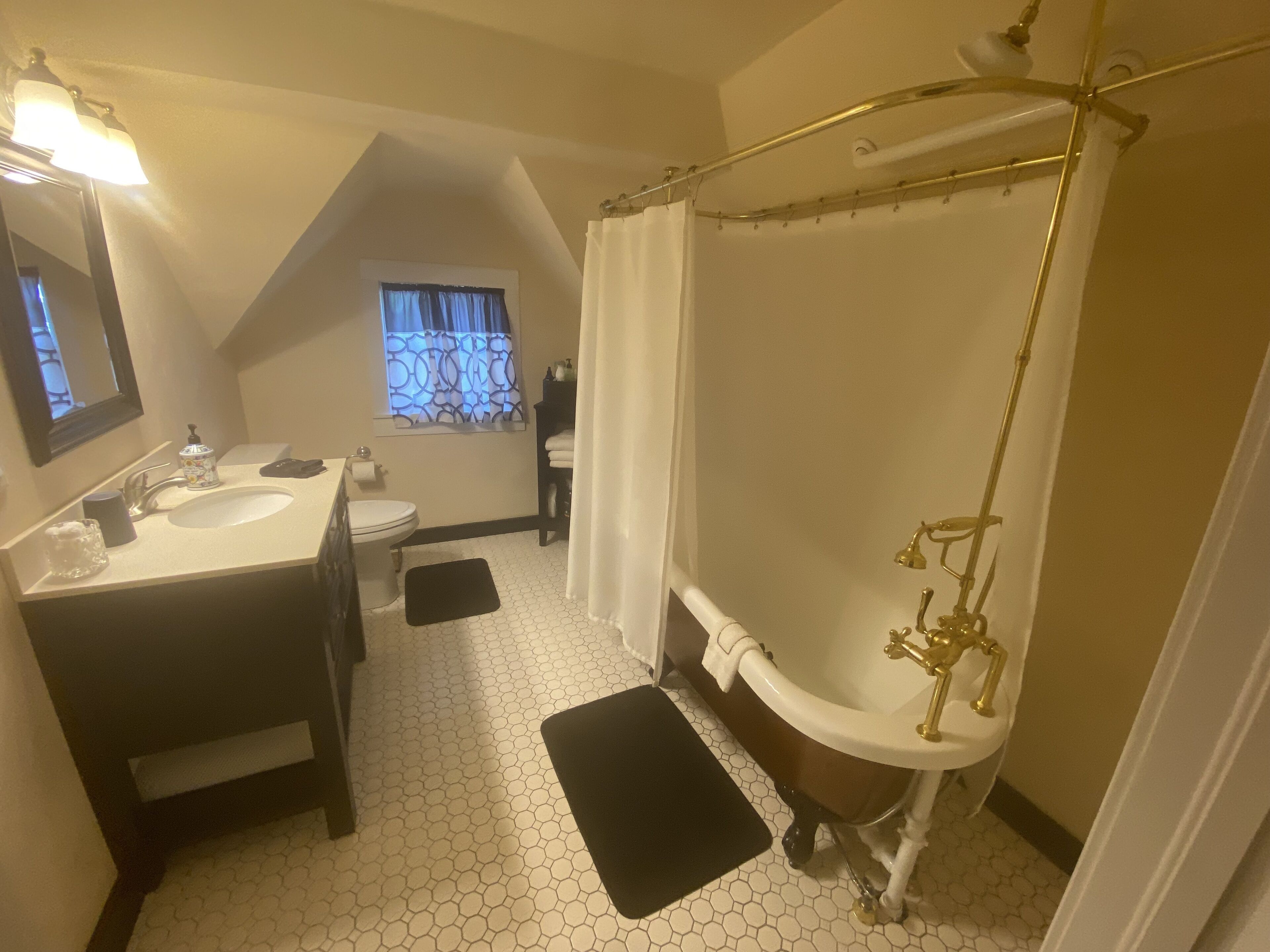 Un baño con lavamanos, inodoro y bañera con cabezal de ducha dorado.