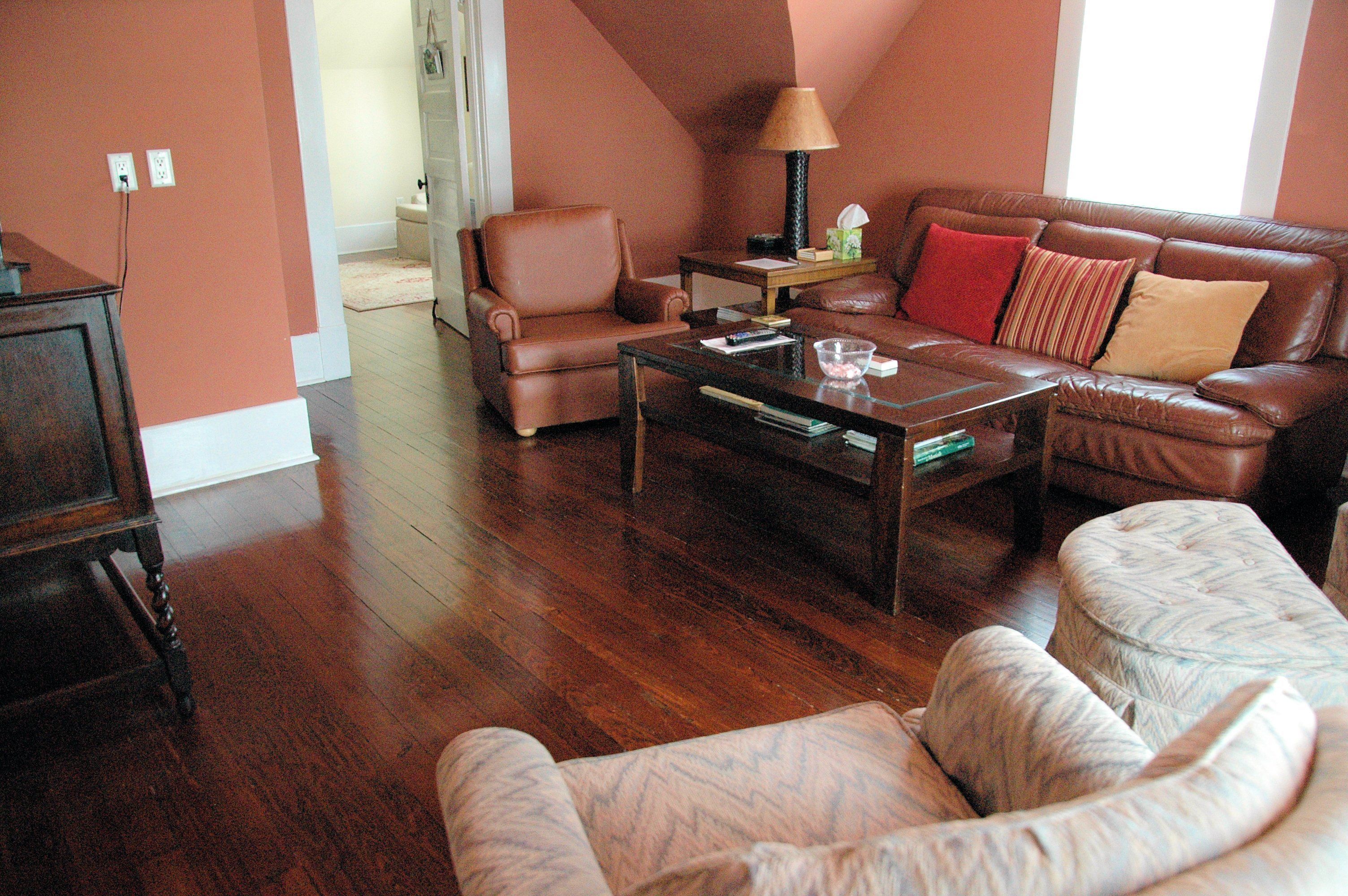 A living room with a brown leather sofa, a coffee table, and a patterned ottoman.