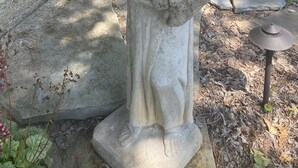 Una estatua de piedra de una persona en un jardín.