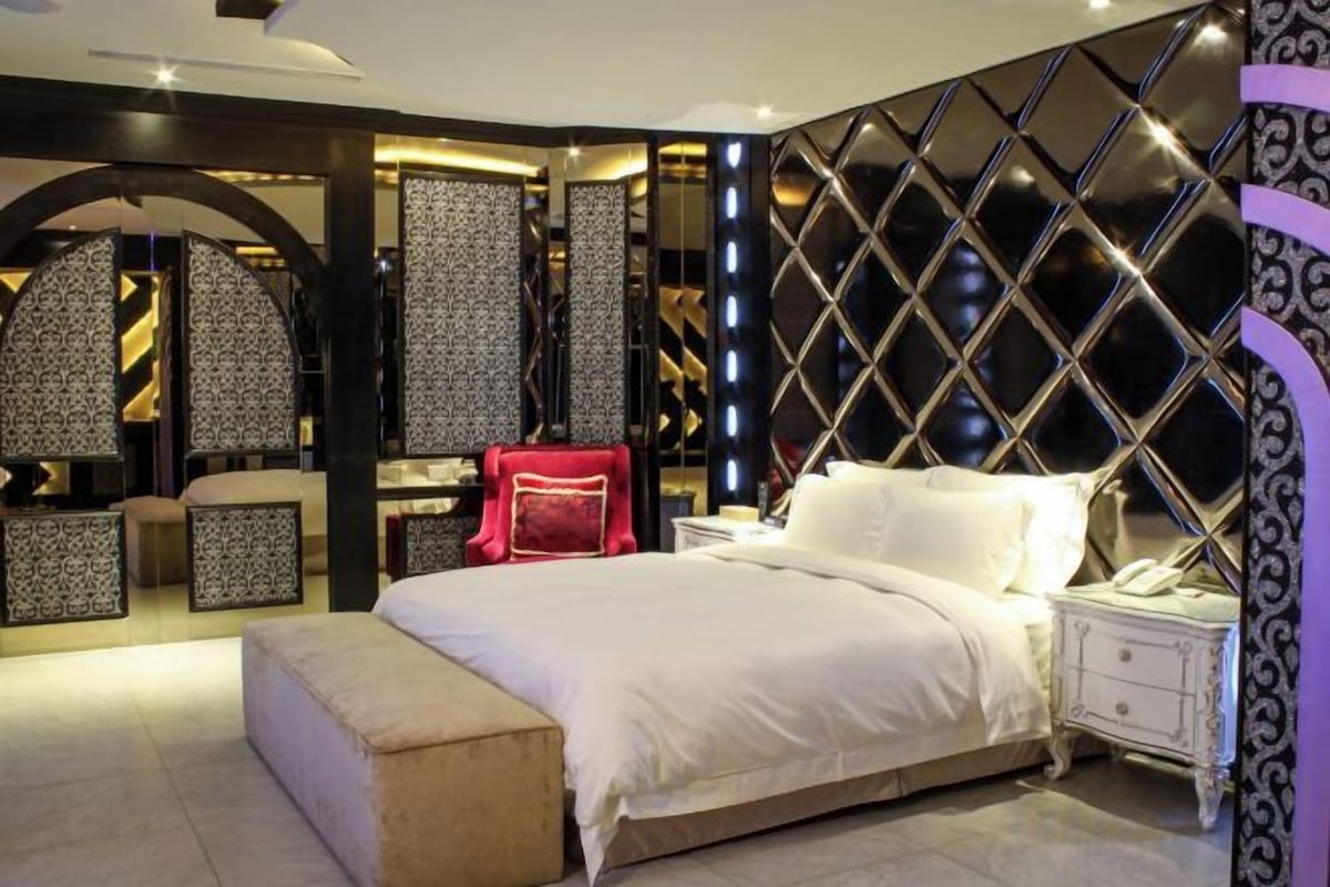 A modern bedroom with a large bed, bedside tables, and a decorative wall.