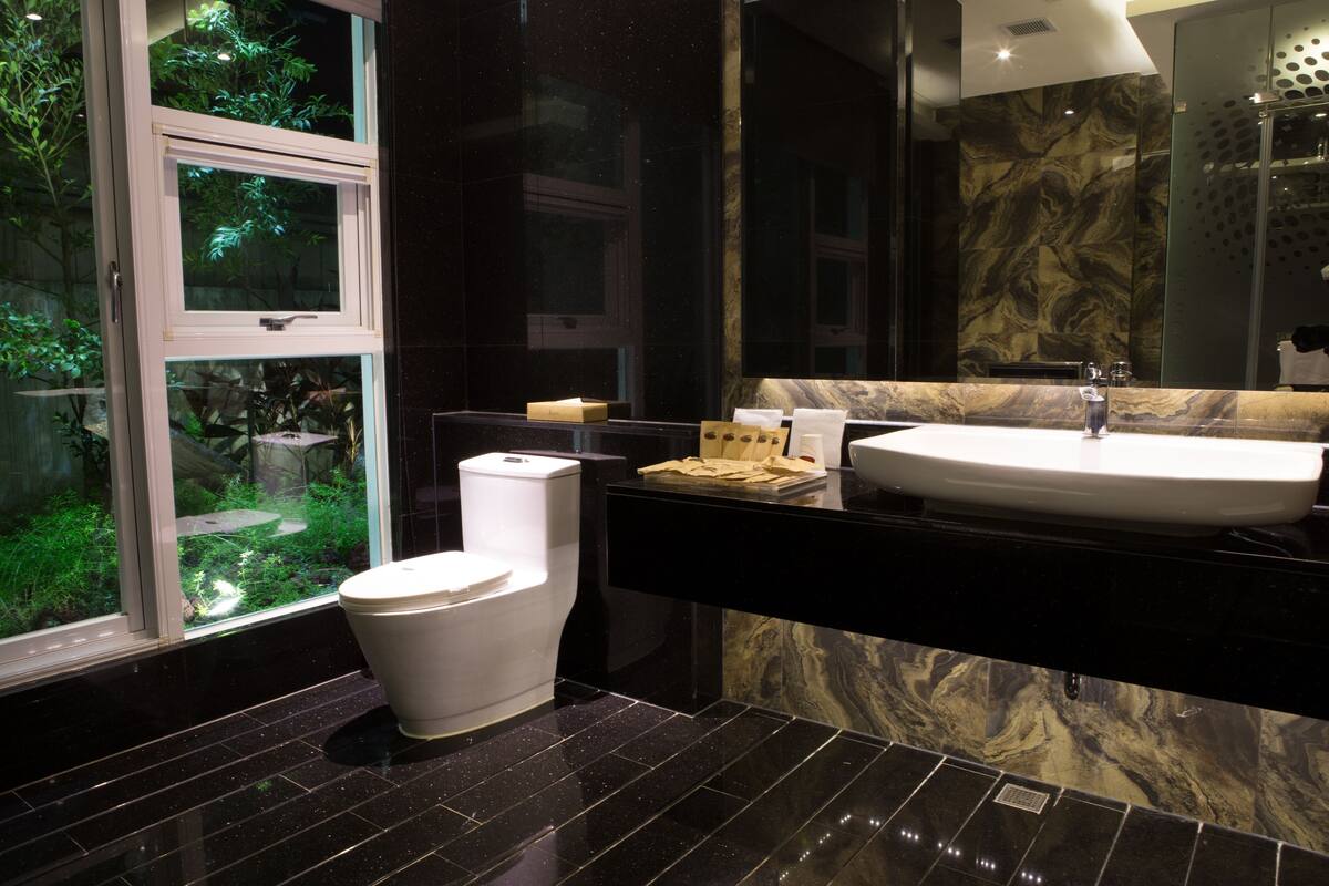Een moderne badkamer met toilet, wastafel en grote spiegel.