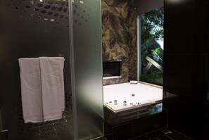 Une salle de bain moderne avec une douche à parois de verre, un mur en marbre et une grande baignoire.