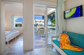 Een hotelkamer met balkon, televisie, bank en bed.