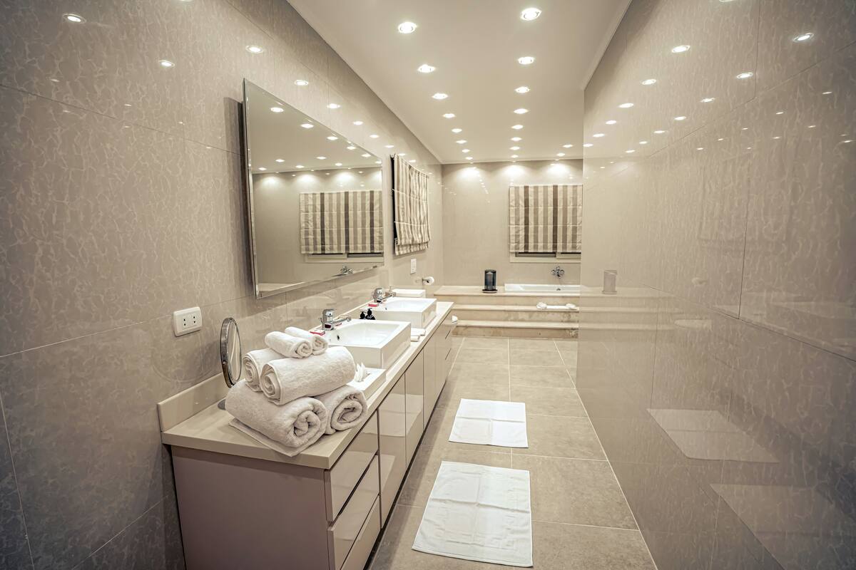 A modern bathroom with two sinks, a large mirror, and a bathtub.