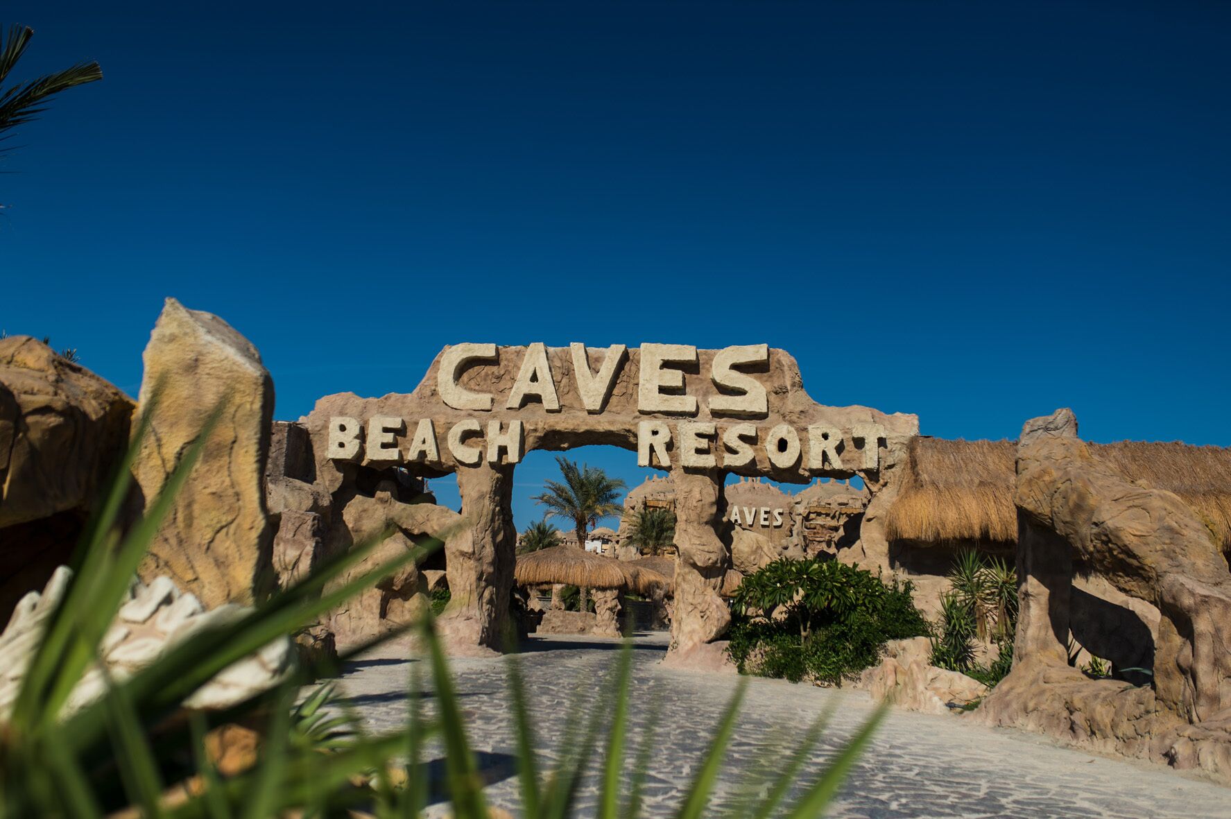 An entrance archway with the text "Caves Beach Resort" and "Aves" indicating the location.