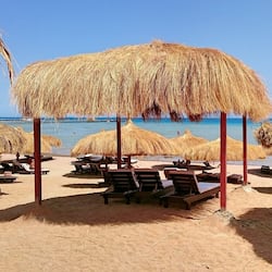 Praia particular, areia branca, espreguiçadeiras, guarda-sóis
