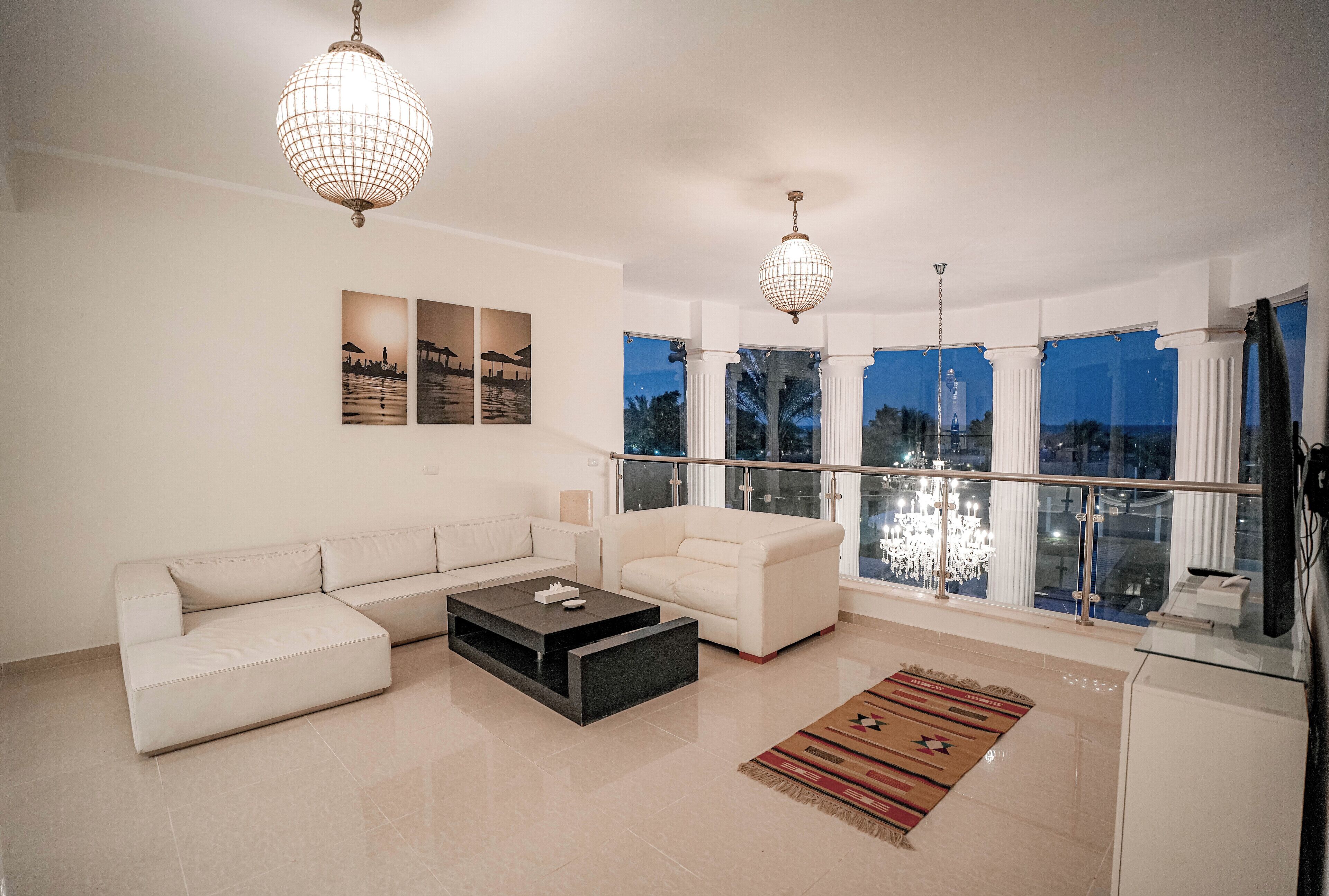A modern living room with a sectional sofa, a coffee table, and a large window with a view of palm trees.
