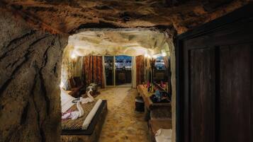 A cave-like room with a bed, a wooden bench, and a table with various items.