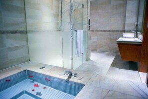 Une salle de bain moderne dotée d’une douche en verre, d’un sol carrelé en marbre et d’un meuble-lavabo en bois.