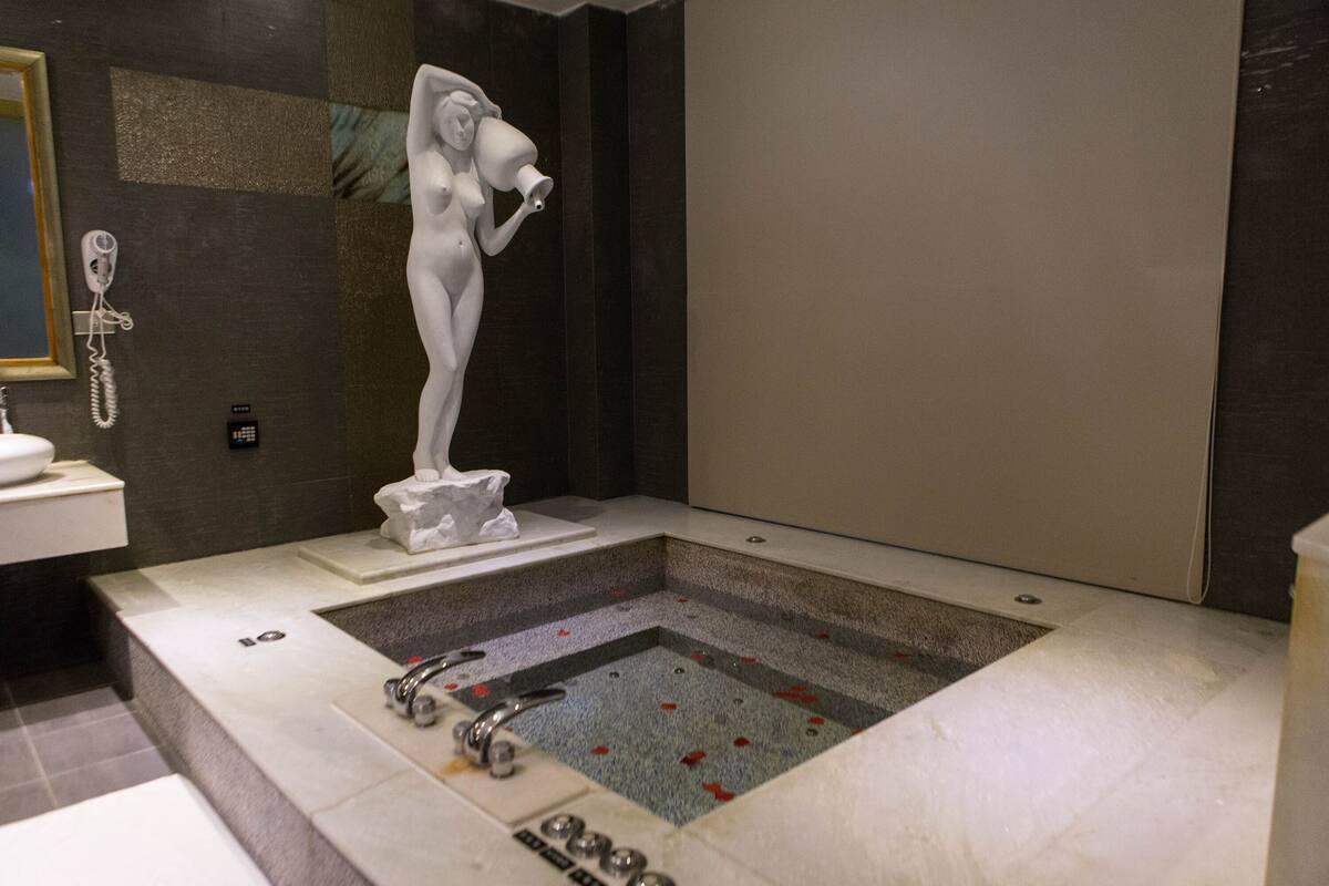 Un baño moderno con una bañera grande, un lavamanos pedestal y un teléfono.