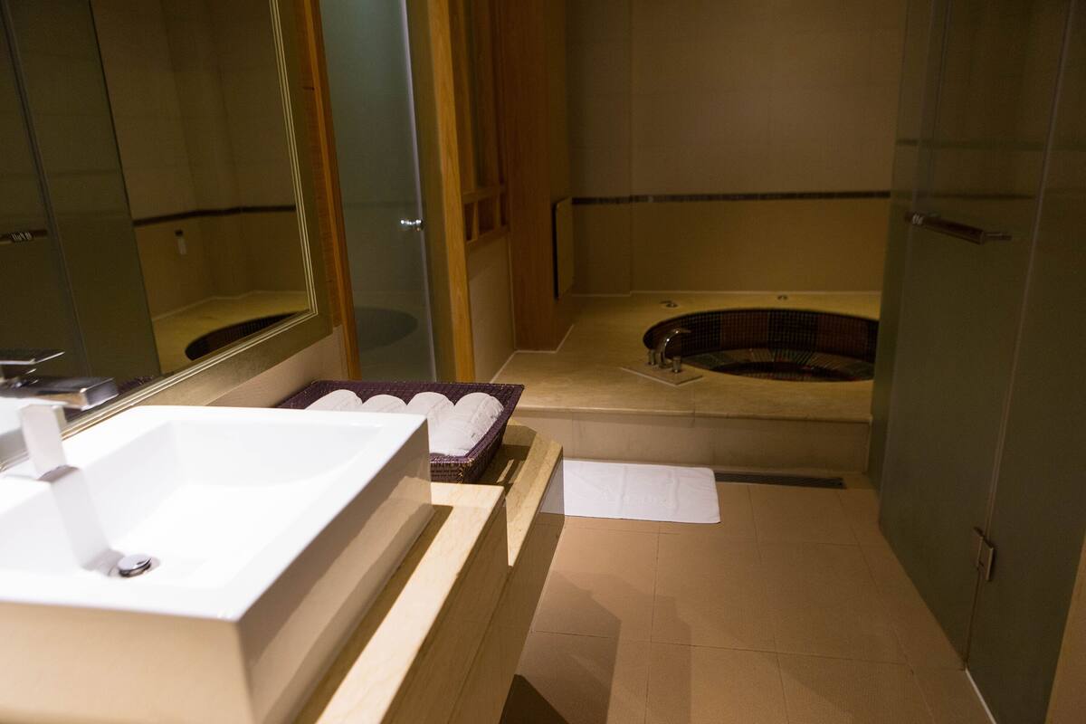 Un baño moderno con un lavabo grande de color blanco, una bañera independiente y un espejo.