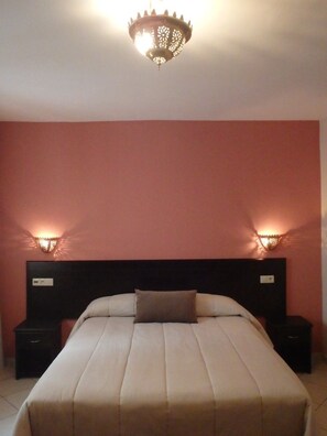 Een hotelkamer met een groot bed, twee nachtkastjes en een kroonluchter.