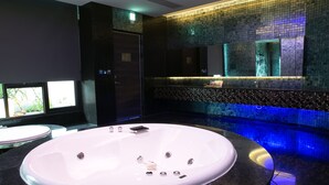 Un baño moderno con una bañera ovalada grande, un lavamanos aparte y un espejo sobre la bañera.