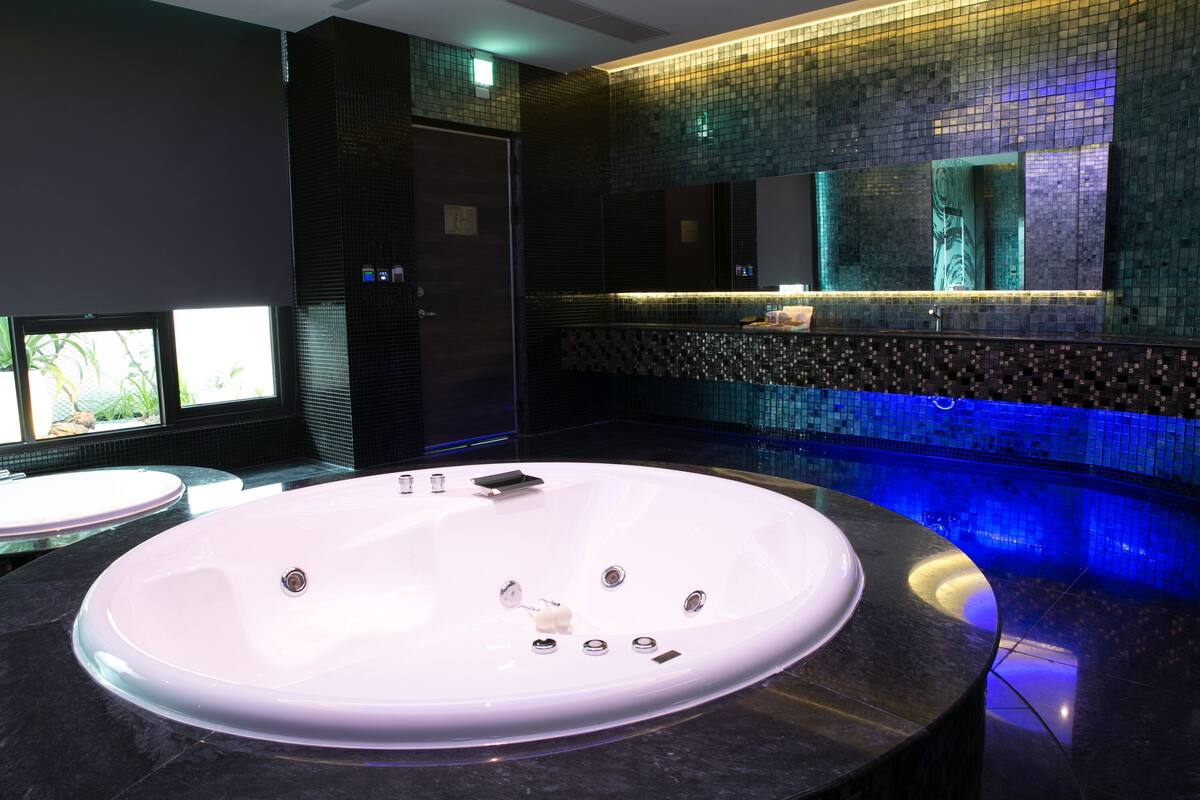 A modern bathroom with a large oval bathtub, a separate sink, and a mirror above the bathtub.