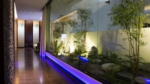 Un vestíbulo moderno con un acuario de vidrio que muestra plantas acuáticas y un sendero iluminado en azul.